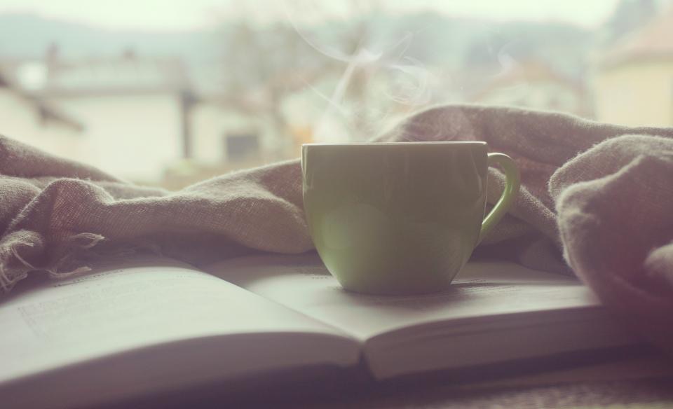 แก้วกาแฟวางบนหนังสือข้างหน้าต่าง